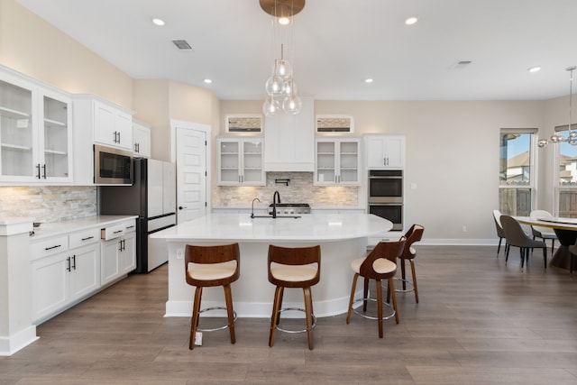 kitchen featuring white cabinets, stainless steel appliances, hanging light fixtures, and dark wood-type flooring