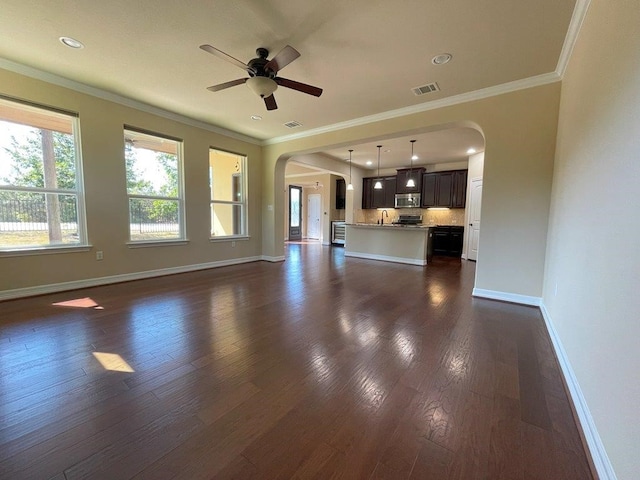 unfurnished living room with ceiling fan, dark wood-type flooring, and ornamental molding