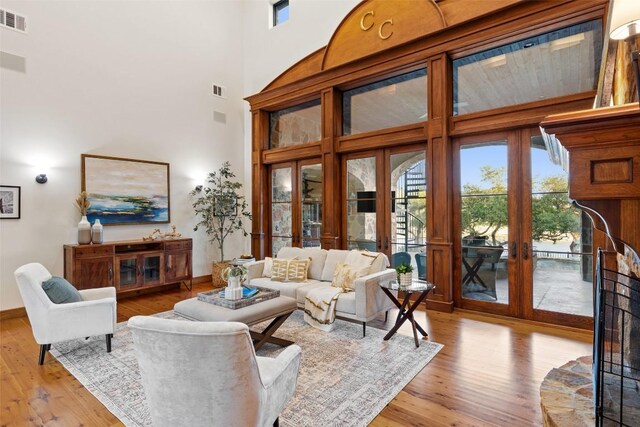 living room with french doors, a high ceiling, and light wood-type flooring