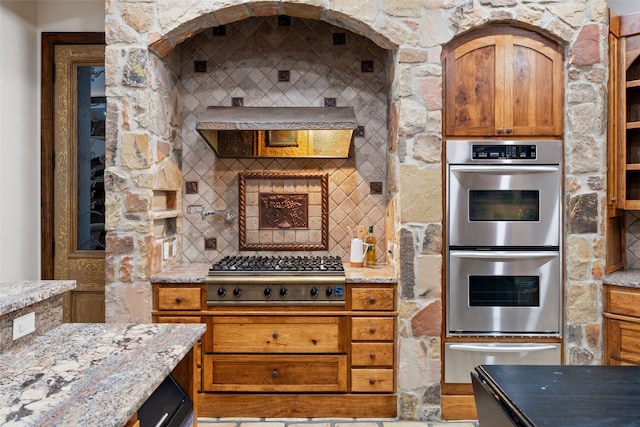 kitchen with decorative backsplash, appliances with stainless steel finishes, and light stone counters