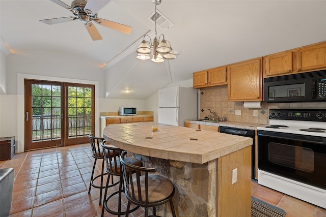 kitchen with a center island, a kitchen breakfast bar, tile countertops, vaulted ceiling, and white appliances