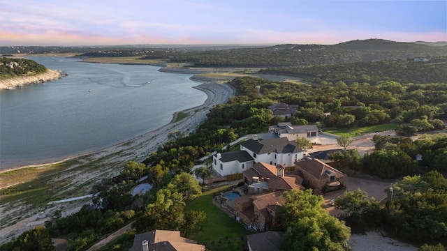 aerial view at dusk featuring a water view