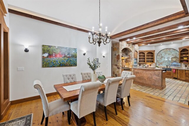 dining area with beamed ceiling, light wood-type flooring, and a notable chandelier