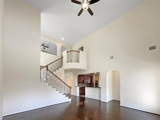 interior space with ceiling fan, a towering ceiling, and dark wood-type flooring