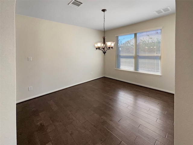 empty room with a chandelier and dark wood-type flooring