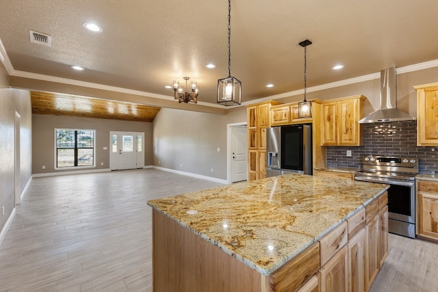 kitchen with appliances with stainless steel finishes, light hardwood / wood-style floors, a kitchen island, and wall chimney range hood