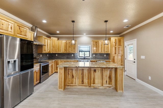 kitchen with pendant lighting, a center island, wall chimney exhaust hood, light stone countertops, and appliances with stainless steel finishes