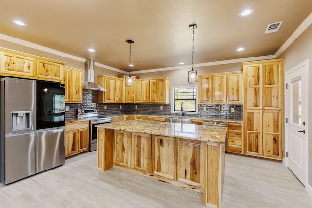 kitchen featuring light stone countertops, wall chimney exhaust hood, stainless steel appliances, a kitchen island, and hanging light fixtures