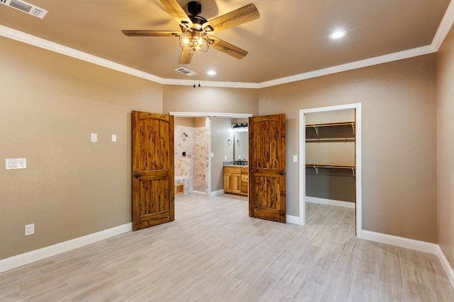 unfurnished bedroom featuring ceiling fan, a walk in closet, ornamental molding, and a closet