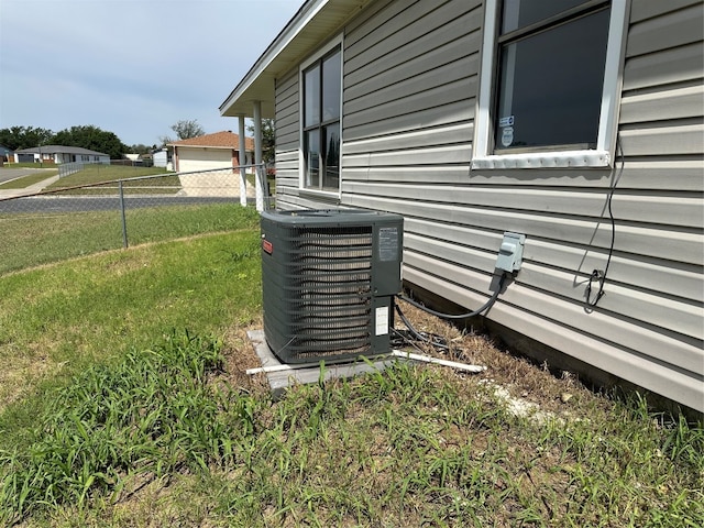 view of side of home with cooling unit and a lawn