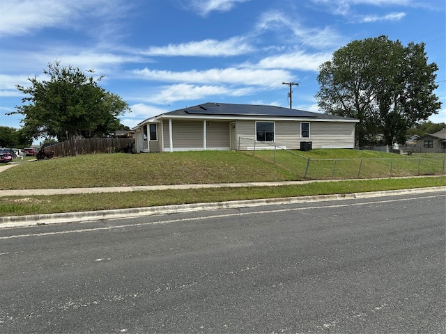 view of front of house with a front yard, solar panels, and central AC unit