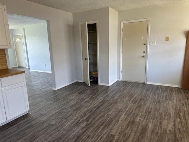 unfurnished living room with dark hardwood / wood-style flooring and a textured ceiling