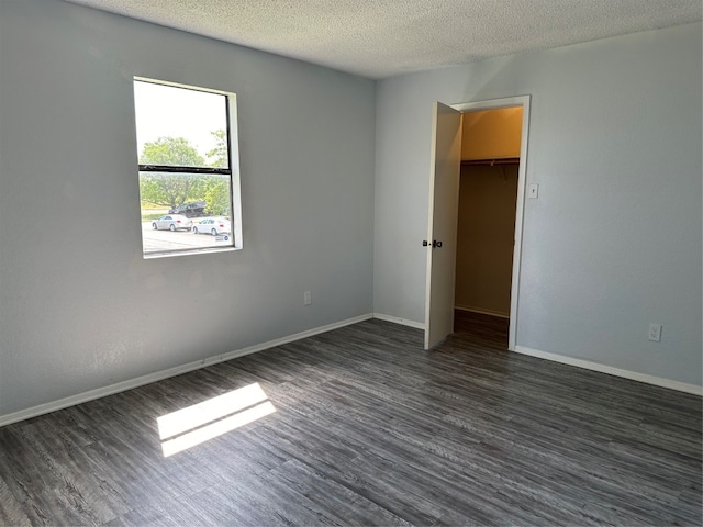 unfurnished room featuring dark wood-type flooring and a textured ceiling