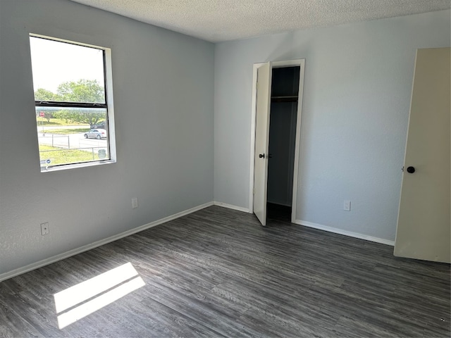 unfurnished bedroom with a textured ceiling, dark wood-type flooring, and a closet