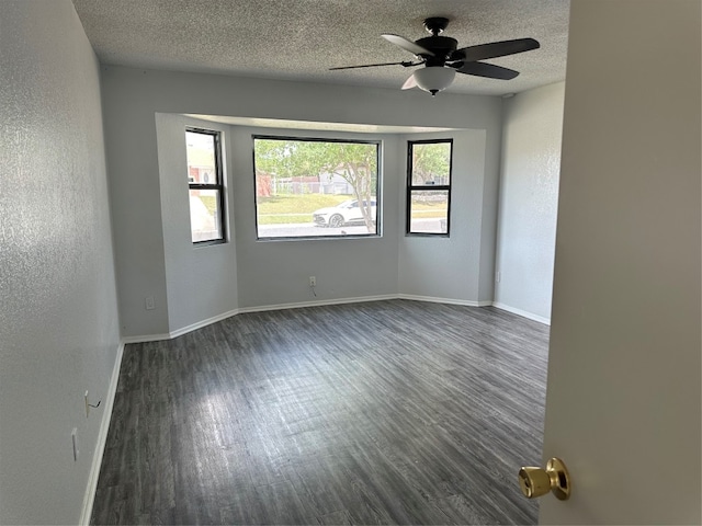 spare room featuring dark hardwood / wood-style floors, ceiling fan, and a textured ceiling