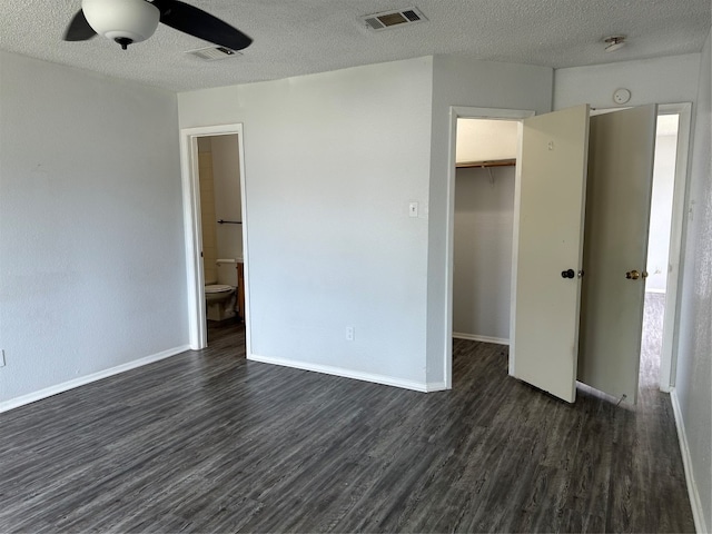 unfurnished bedroom featuring ceiling fan, a spacious closet, dark hardwood / wood-style flooring, a textured ceiling, and a closet