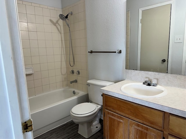 full bathroom featuring tiled shower / bath combo, toilet, wood-type flooring, and vanity