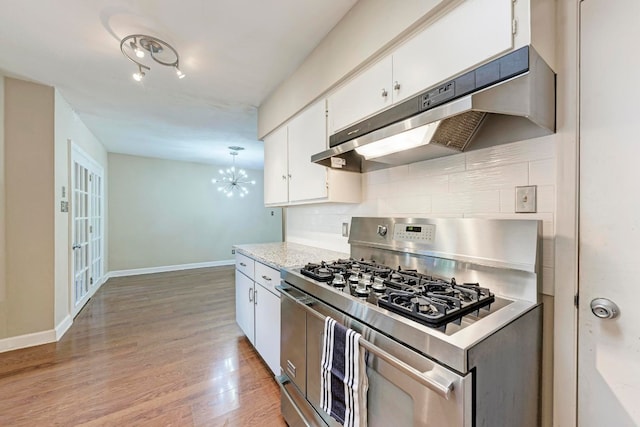 kitchen with gas range, pendant lighting, a notable chandelier, white cabinets, and light hardwood / wood-style floors