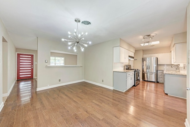 kitchen featuring sink, stainless steel appliances, an inviting chandelier, light hardwood / wood-style flooring, and white cabinets