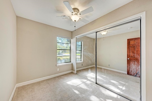 unfurnished bedroom featuring ceiling fan, light colored carpet, and a closet