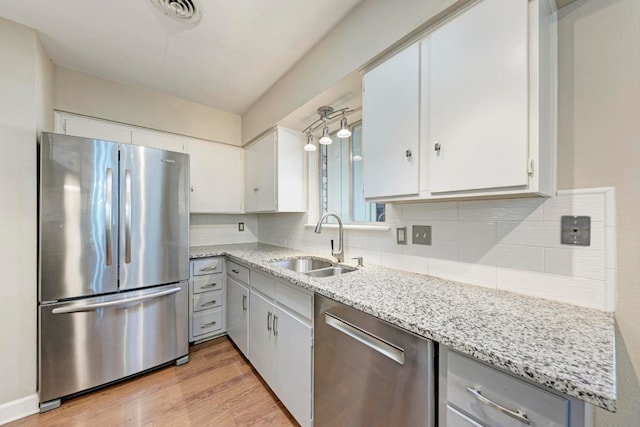 kitchen with white cabinets, sink, light hardwood / wood-style flooring, tasteful backsplash, and stainless steel appliances