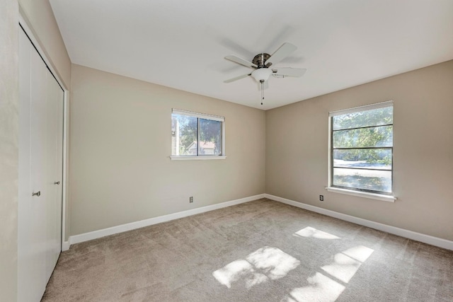 unfurnished bedroom with light carpet, multiple windows, and ceiling fan