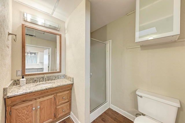 bathroom with hardwood / wood-style floors, vanity, toilet, and an enclosed shower