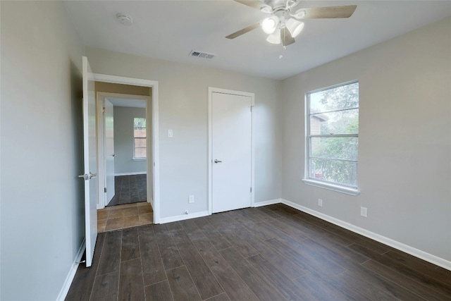 unfurnished bedroom with ceiling fan, dark wood-type flooring, and a closet