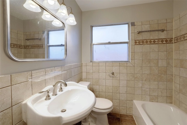 bathroom with sink, a healthy amount of sunlight, tile walls, and toilet