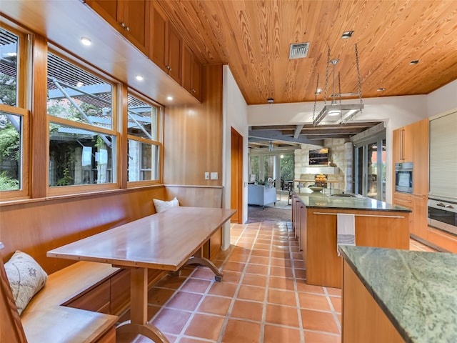 kitchen featuring a center island, breakfast area, decorative light fixtures, wood ceiling, and appliances with stainless steel finishes