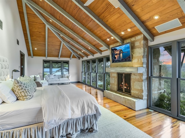 bedroom featuring beam ceiling, a stone fireplace, hardwood / wood-style floors, and wooden ceiling