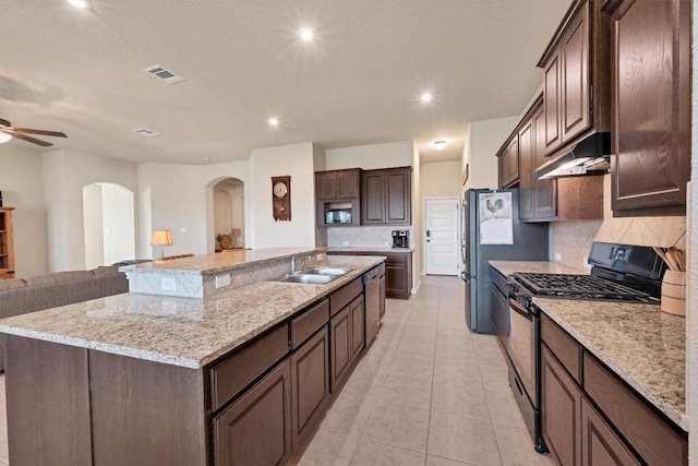 19316 Chayton Cir, Pflugerville, TX 78660 - kitchen featuring under cabinet range hood, appliances with stainless steel finishes, a sink, arched walkways, and backsplash