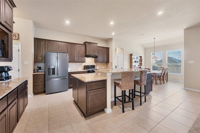 19316 Chayton Cir, Pflugerville, TX 78660 - kitchen with stainless steel fridge, black gas range, decorative backsplash, dark brown cabinets, and a large island with sink