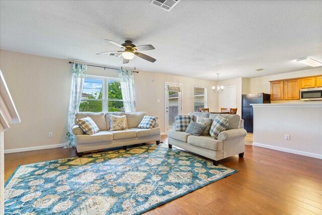 living room featuring dark hardwood / wood-style floors, a textured ceiling, and ceiling fan with notable chandelier