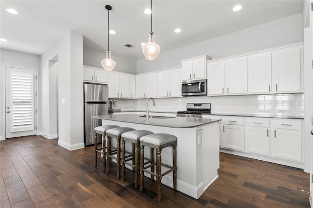 kitchen featuring white cabinetry, sink, dark wood-type flooring, stainless steel appliances, and decorative light fixtures