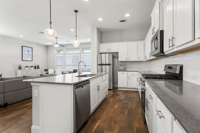 kitchen with stainless steel appliances, white cabinetry, and dark hardwood / wood-style floors