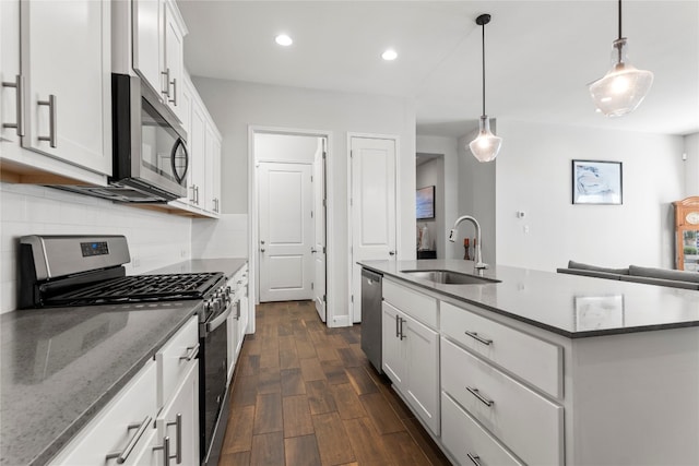 kitchen with appliances with stainless steel finishes, a kitchen island with sink, dark wood-type flooring, sink, and white cabinetry