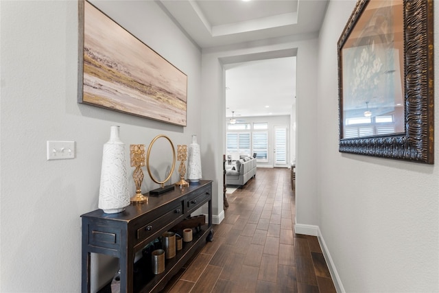 hallway featuring a raised ceiling and dark wood-type flooring