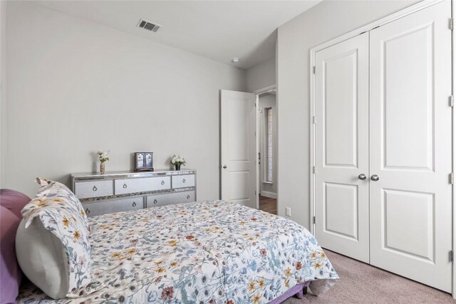 bedroom with a closet, visible vents, and carpet flooring