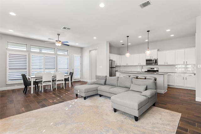 living room with ceiling fan, sink, and dark wood-type flooring