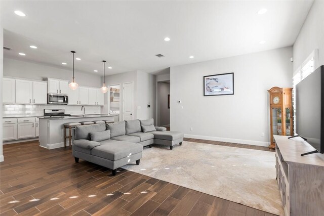 living area featuring visible vents, recessed lighting, dark wood-style flooring, and baseboards