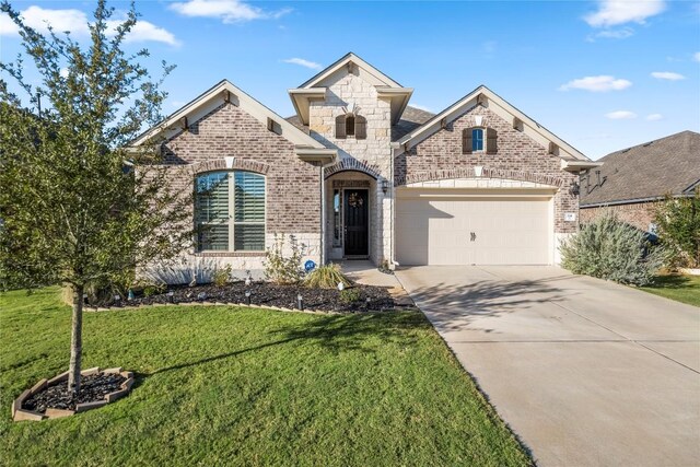 french country home featuring concrete driveway, a garage, brick siding, and a front lawn