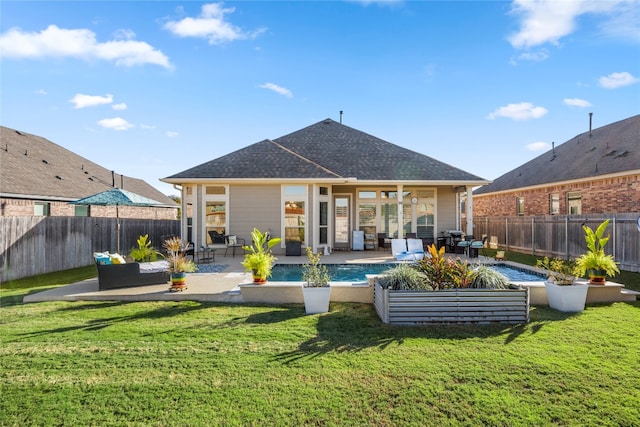 rear view of property with a lawn, a fenced in pool, an outdoor hangout area, and a patio