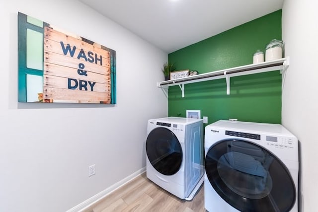 clothes washing area featuring washer and clothes dryer and light hardwood / wood-style floors