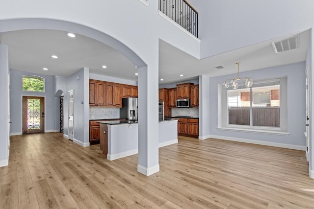 kitchen featuring appliances with stainless steel finishes, tasteful backsplash, a chandelier, a kitchen island, and hanging light fixtures