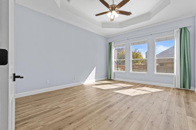 spare room with ceiling fan, a raised ceiling, ornamental molding, and light hardwood / wood-style flooring