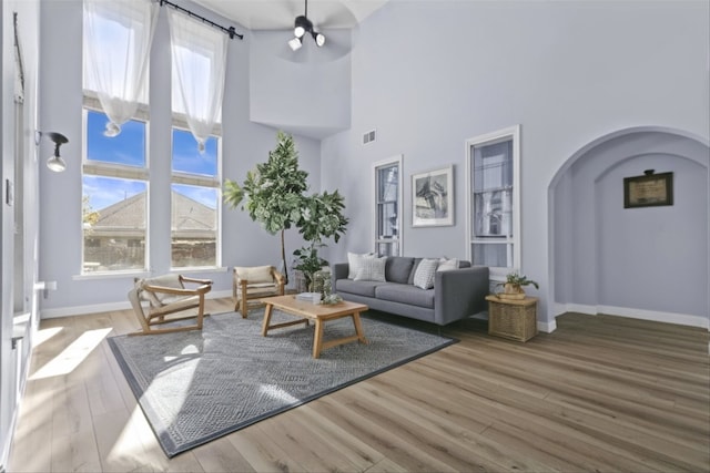 living room featuring hardwood / wood-style floors, ceiling fan, and a high ceiling