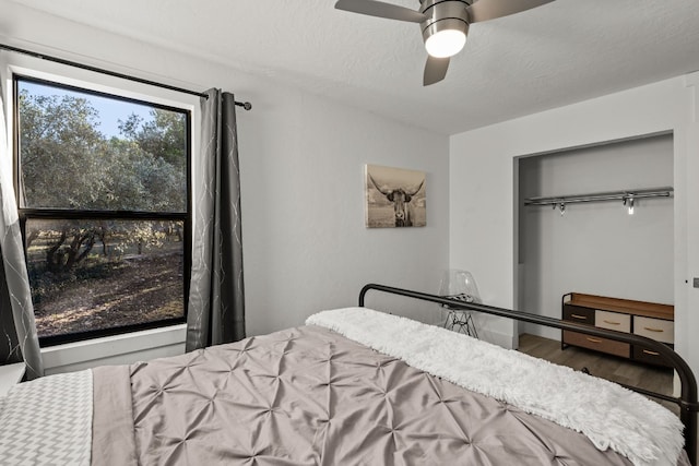 bedroom with ceiling fan, a closet, wood-type flooring, and a textured ceiling