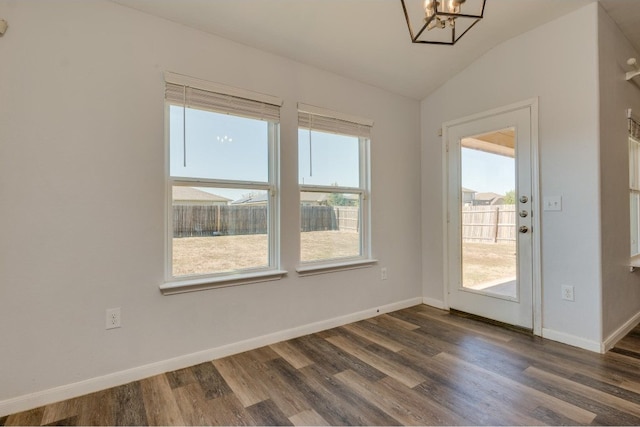 unfurnished dining area with a chandelier, dark hardwood / wood-style flooring, vaulted ceiling, and plenty of natural light