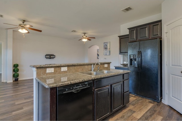 kitchen featuring sink, dark wood-type flooring, a kitchen island with sink, dark brown cabinets, and black appliances